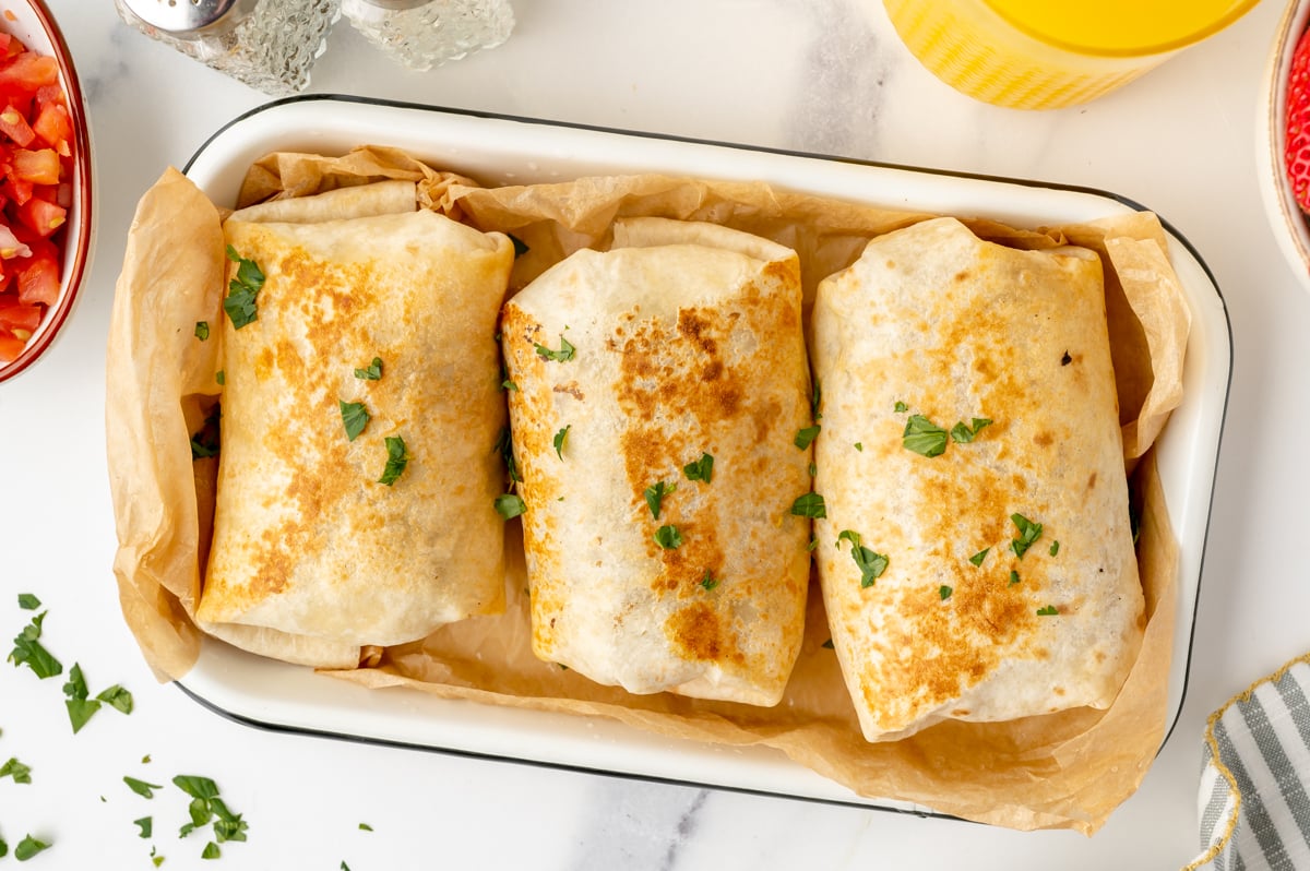 overhead shot of three breakfast burritos in a tray