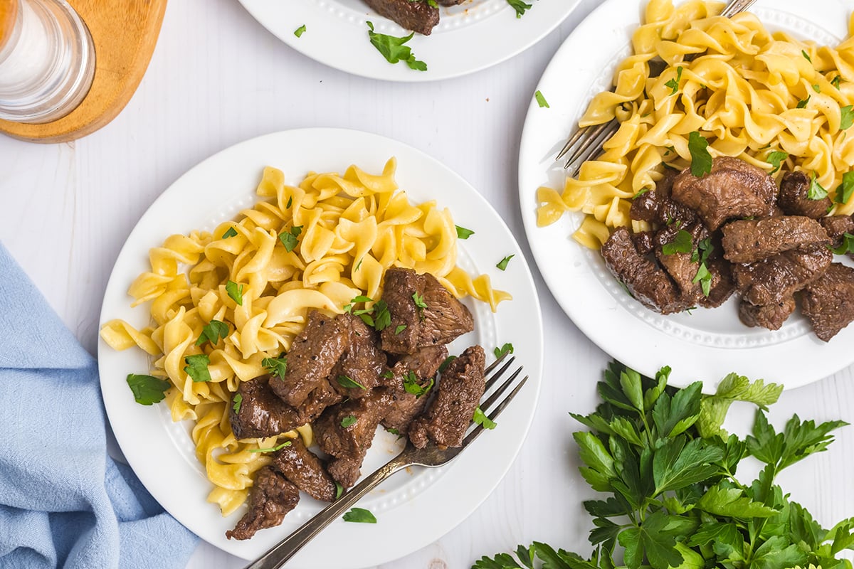 overhead shot of two plates of brown sugar steak tips with noodles