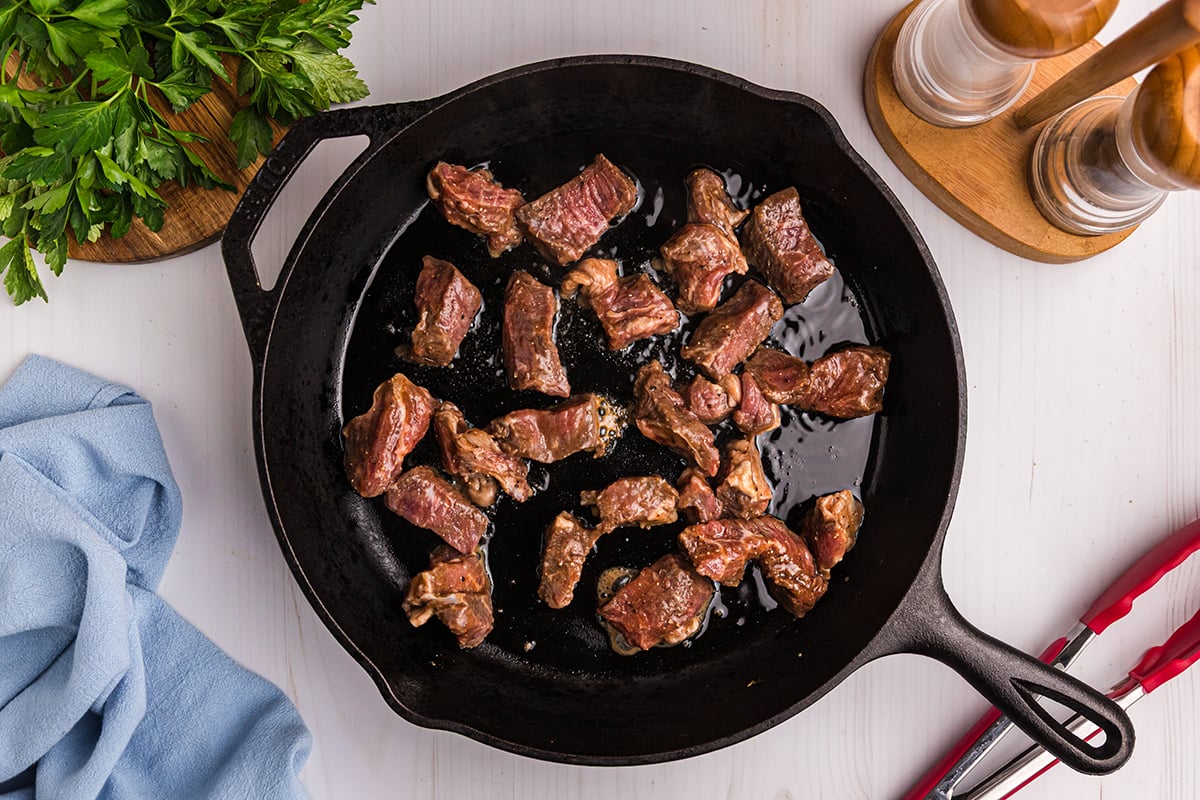 pieces of steak cooking in skillet