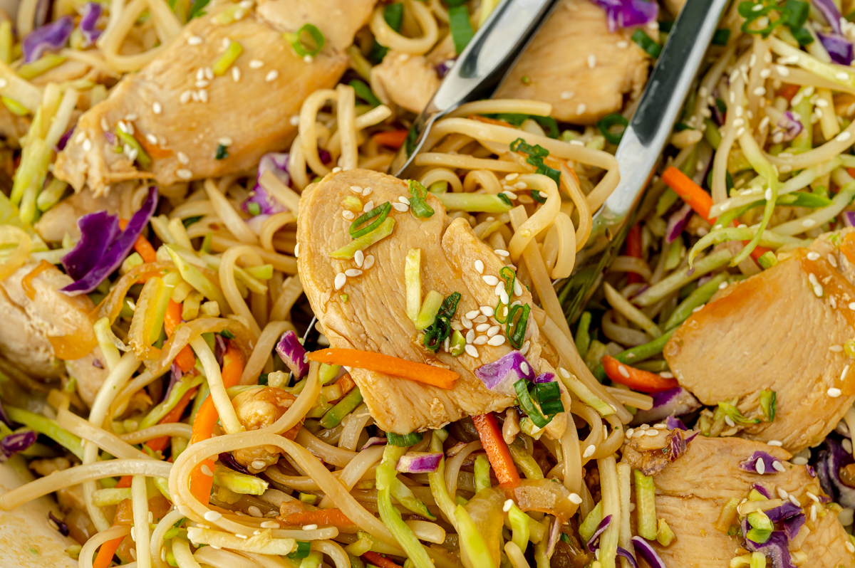 chicken stir fry rice noodles in tongs