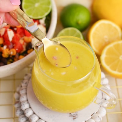 angled shot of spoon in jar of citrus salad dressing