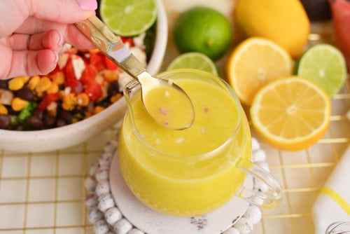 angled shot of spoon in jar of citrus salad dressing