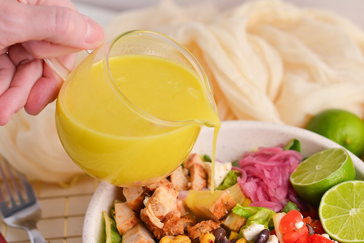 hand pouring citrus vinaigrette over salad