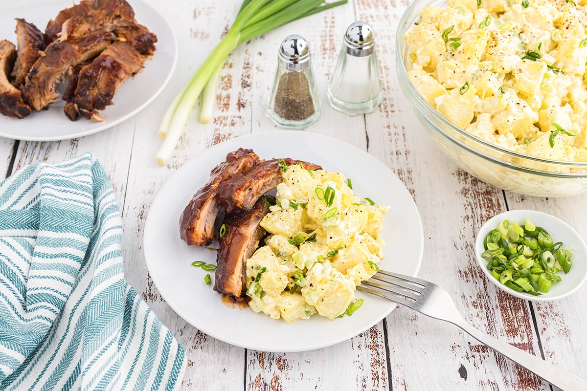 angled shot of plate of ribs and potato salad with fork on it