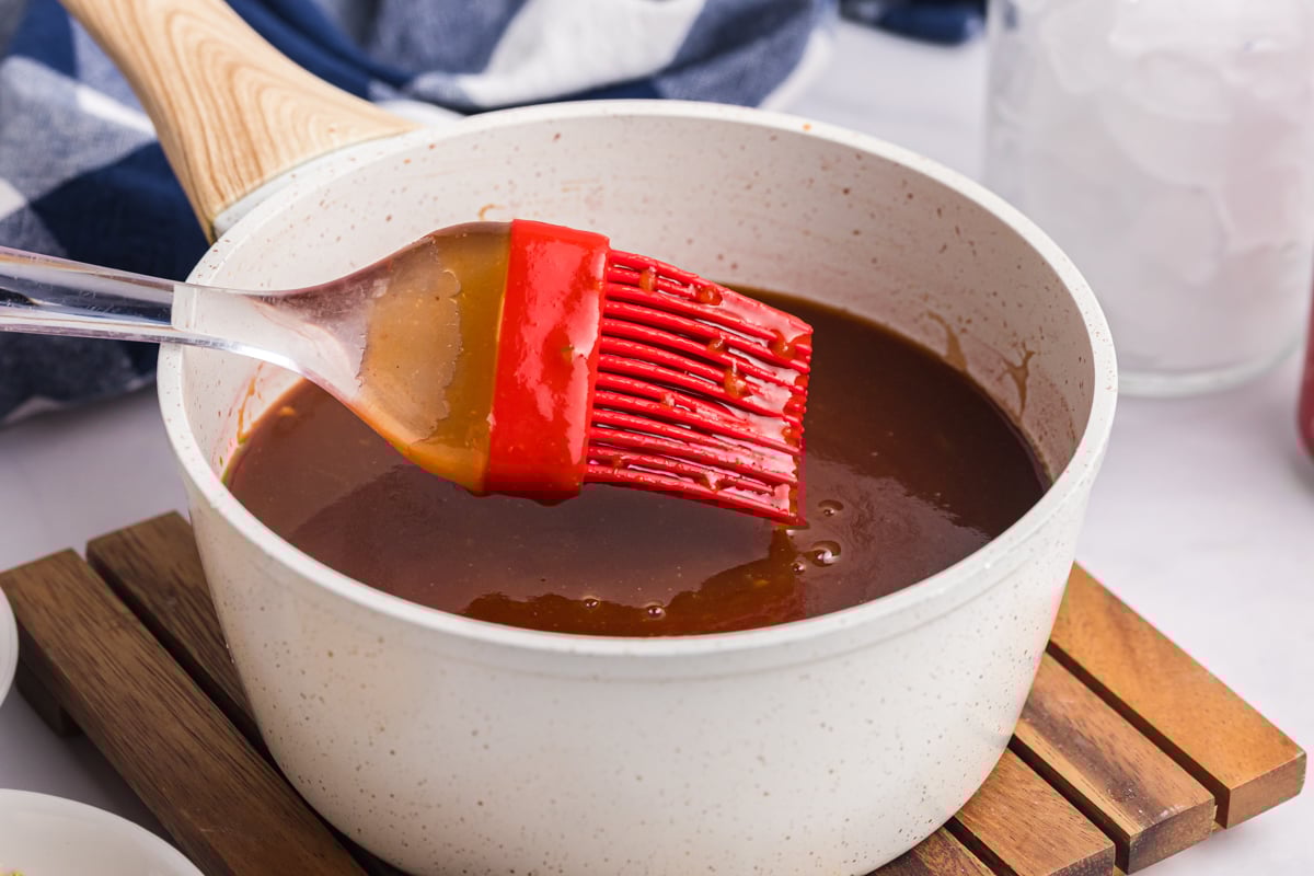 angled shot of silicone brush in saucepan of cola bbq sauce