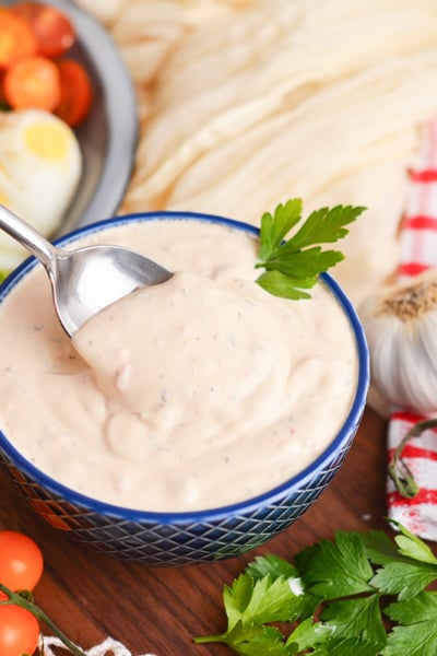 angled shot of spoon in bowl of creamy italian dressing