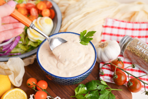 angled shot of spoon in bowl of creamy italian dressing