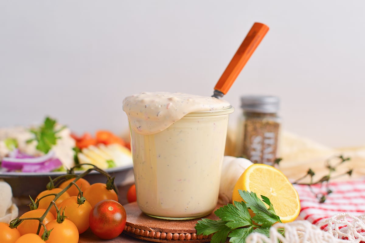 straight on shot of spoon in jar of creamy italian dressing