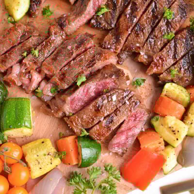 close up overhead shot of sliced steak on board with veggies