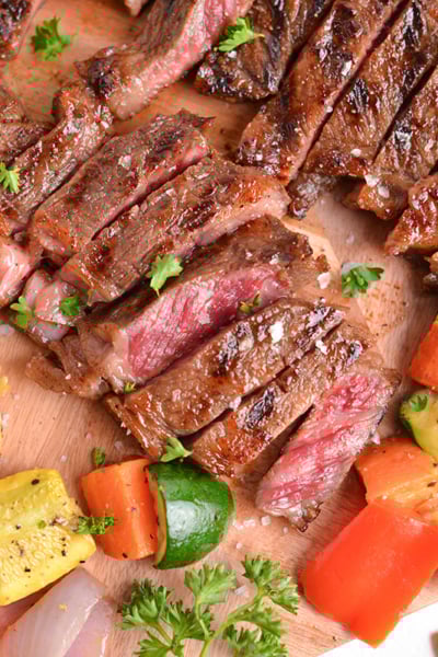 close up overhead shot of sliced steak on board with veggies
