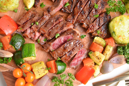 close up overhead shot of sliced steak on board with veggies