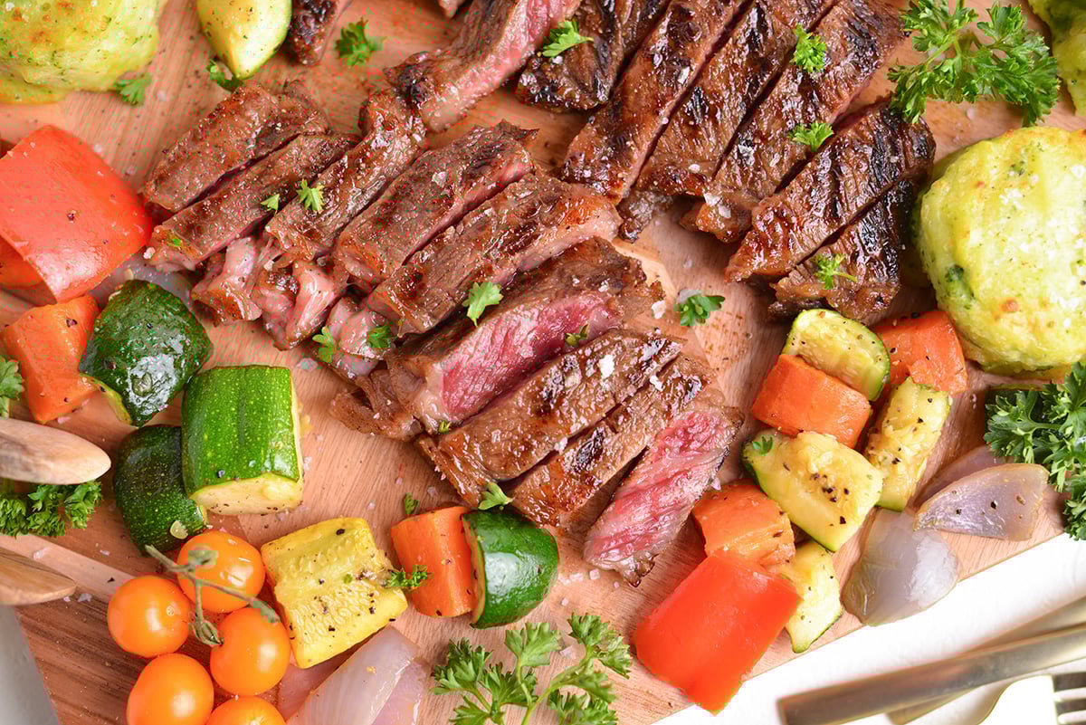 close up overhead shot of sliced steak on board with veggies