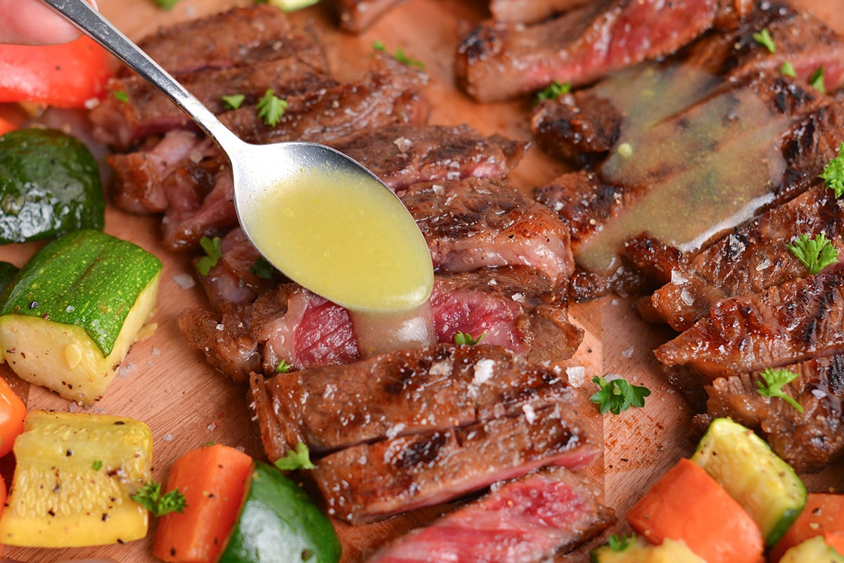 spoon adding garlic butter to sliced steak
