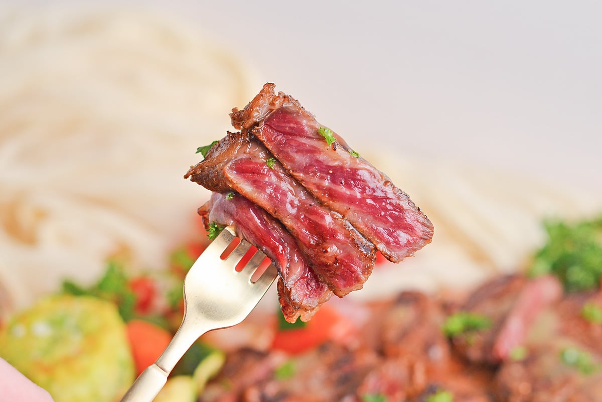 bite of rare steak on fork