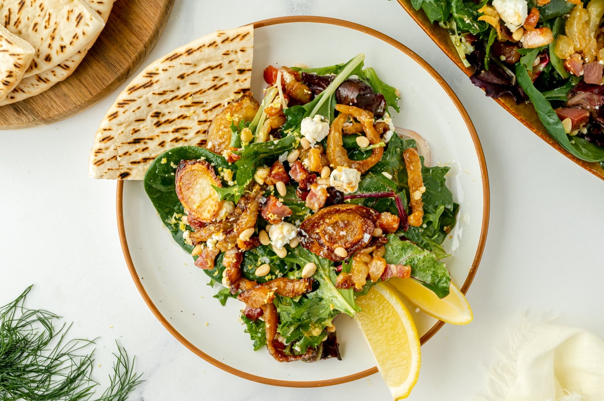 overhead shot of fennel salad on plater with pita and lemon wedges