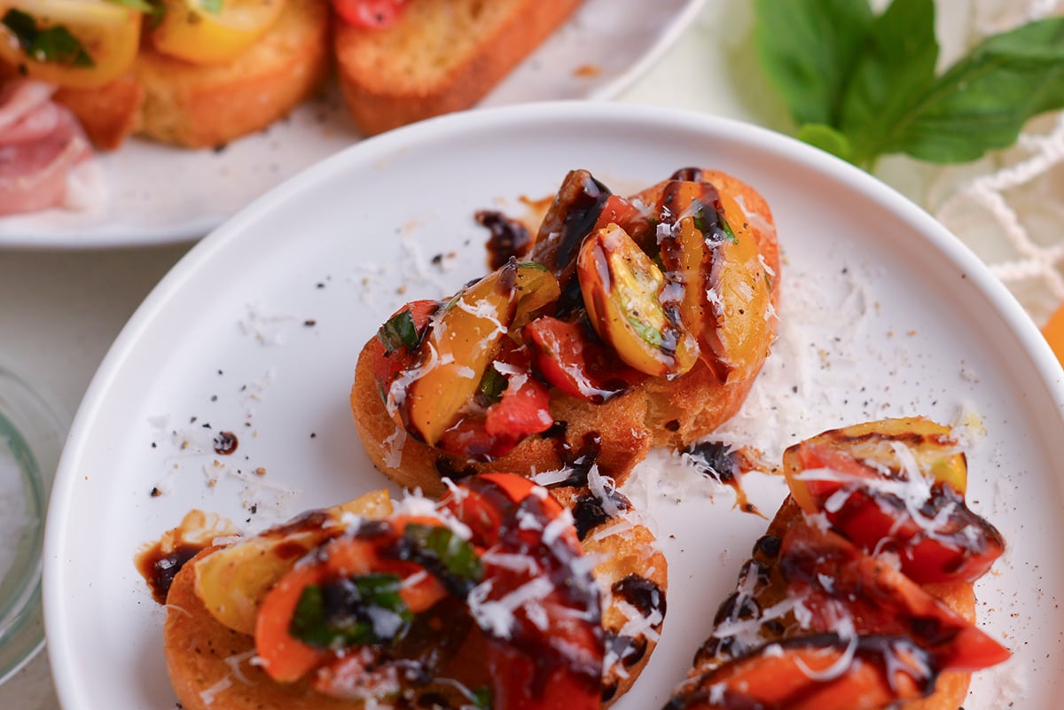 close up angled shot of tomato bruschetta on plate drizzled with balsamic