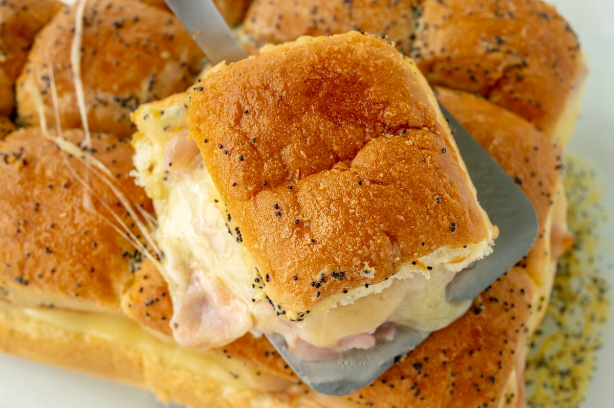 close up angled shot of ham and cheese slider on spatula