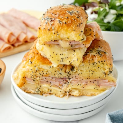 angled shot of pile of ham and cheese sliders on plate