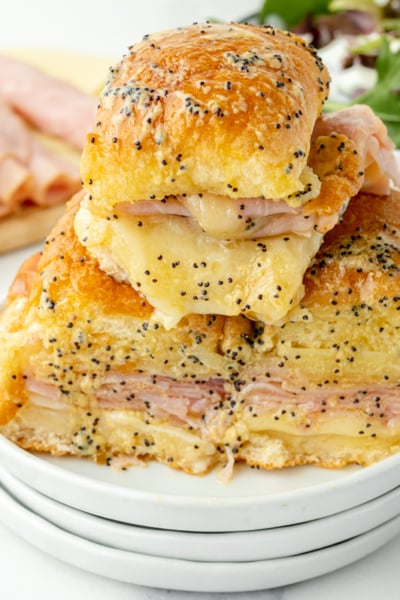 angled shot of pile of ham and cheese sliders on plate