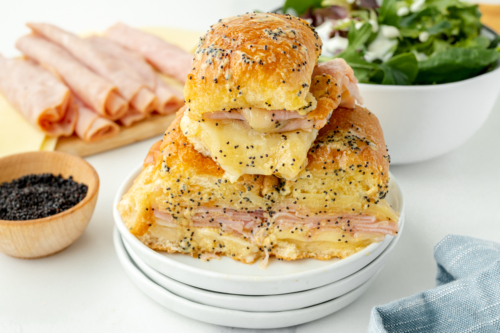 angled shot of pile of ham and cheese sliders on plate