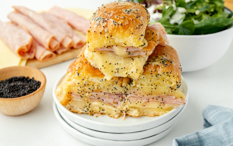 angled shot of pile of ham and cheese sliders on plate