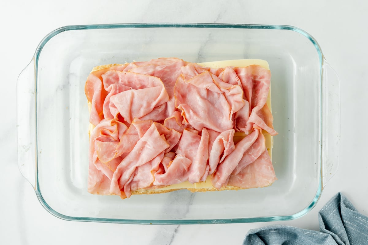 overhead shot of ham slices on top of rolls in baking dish
