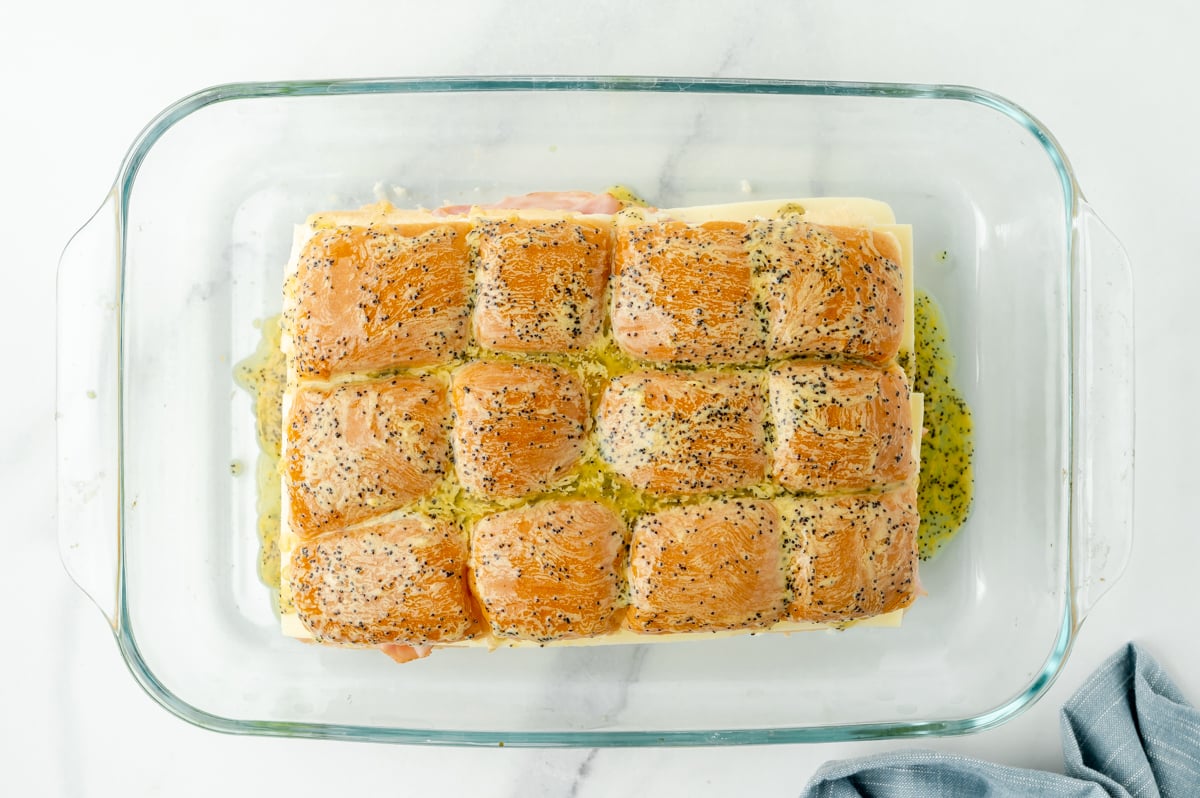 overhead shot of melted butter sauce over sliders in baking dish