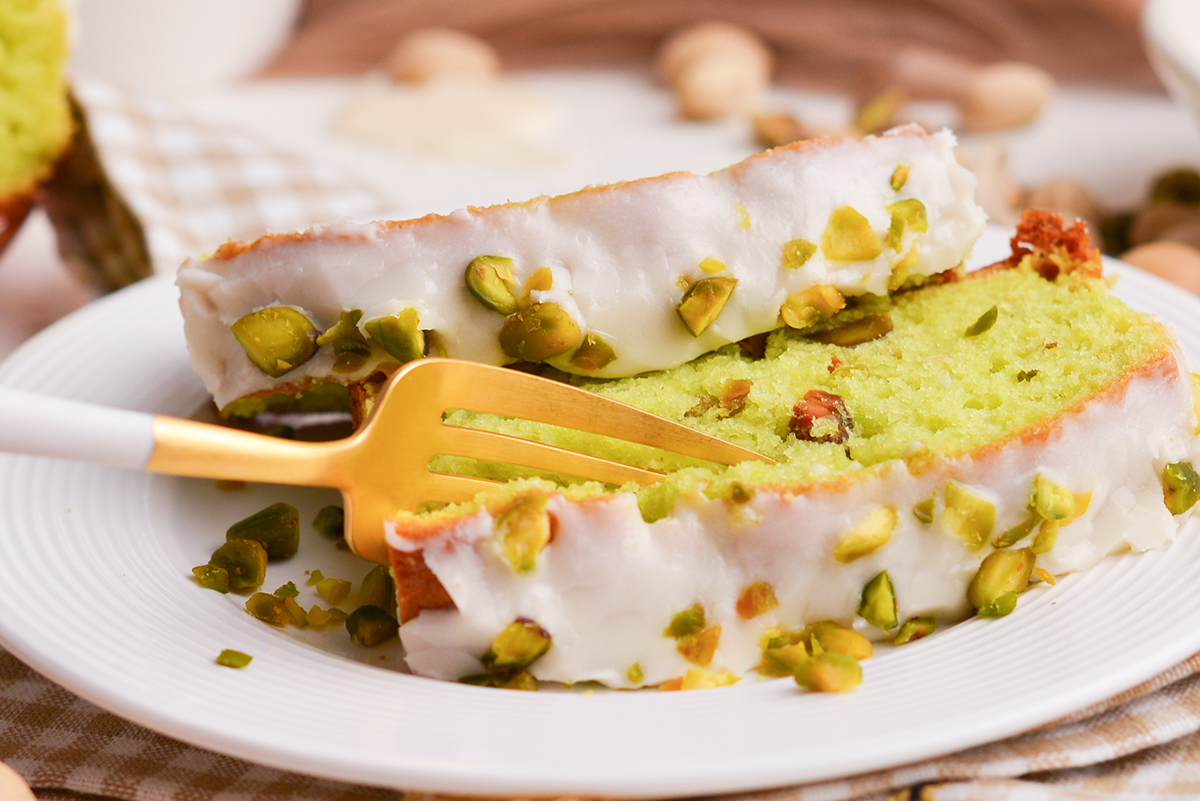 fork digging into slice of pistachio cake