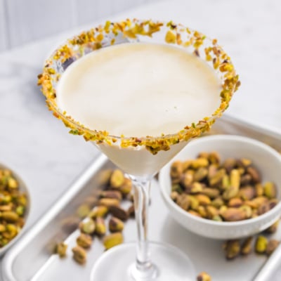 angled shot of pistachio martini on tray with bowl of pistachios