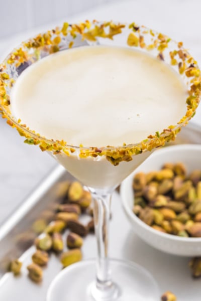 angled shot of pistachio martini on tray with bowl of pistachios