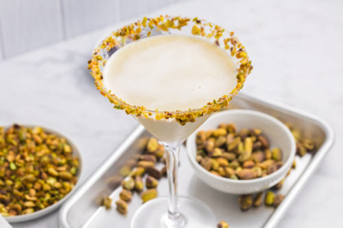 angled shot of pistachio martini on tray with bowl of pistachios