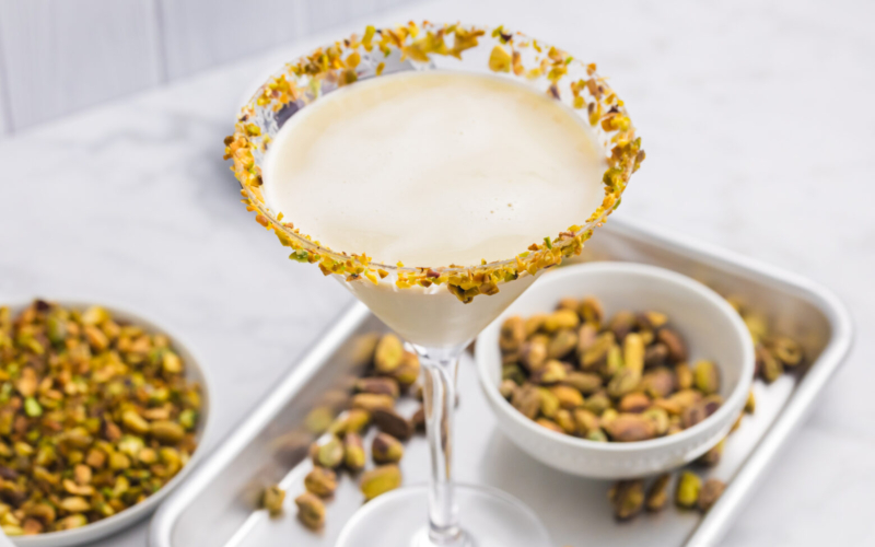 angled shot of pistachio martini on tray with bowl of pistachios