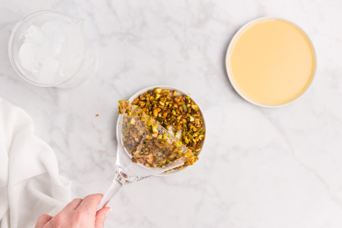 martini glass rim dipping into bowl of crushed pistachios