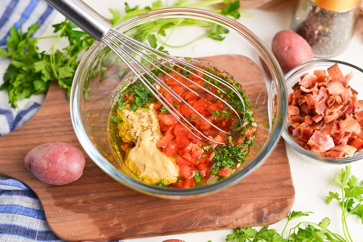 angled shot of dressing ingredients in bowl with whisk