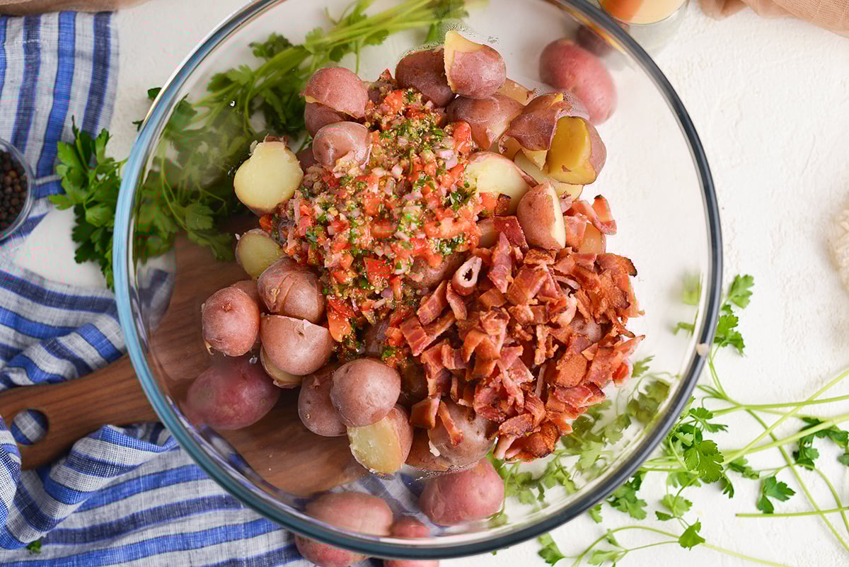 overhead shot of dressing and bacon in bowl of potatoes