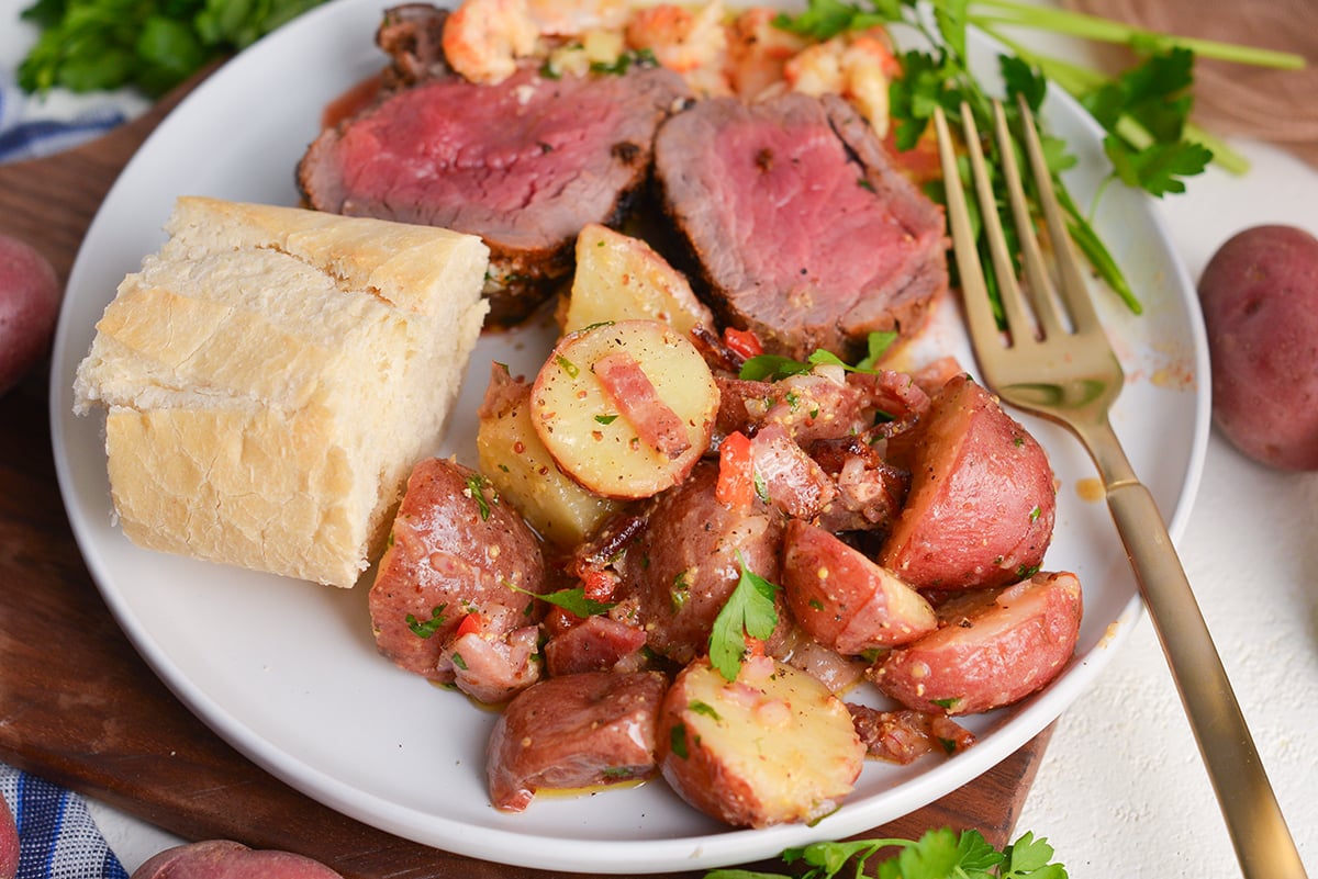 german potato salad on plate with bread, beef and a fork