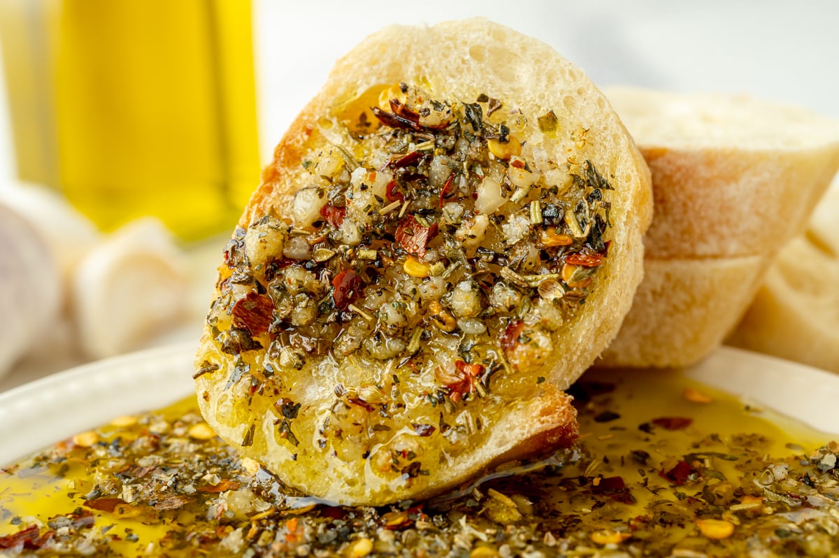 angled shot of slice of bread dipping into olive oil bread dip