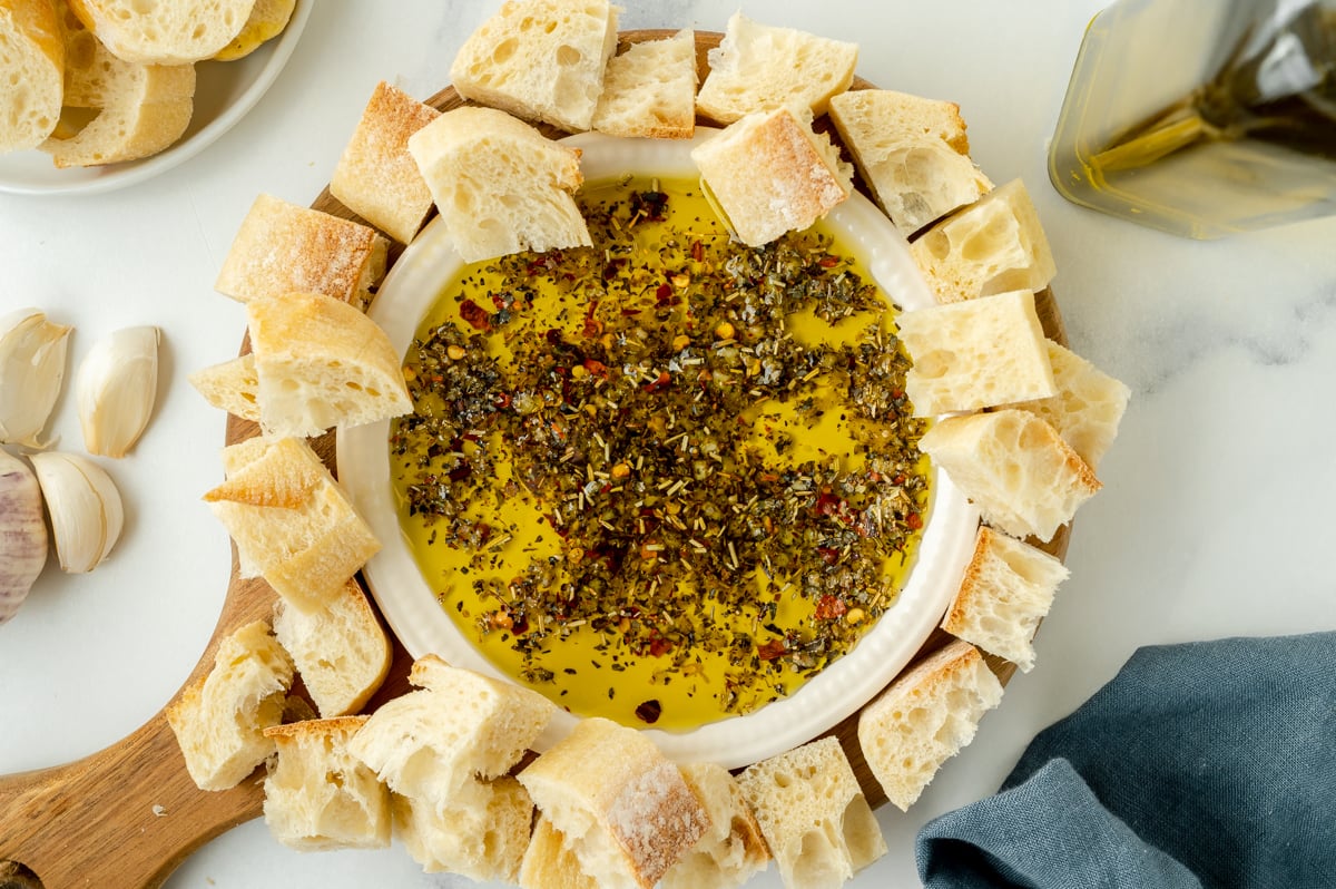 overhead shot of plate of olive oil bread dip surrounded by pieces of bread