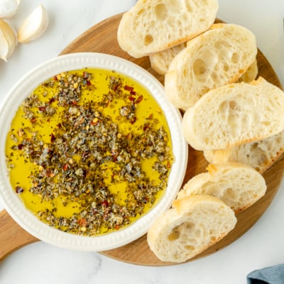 overhead shot of olive oil bread dip on board with bread slices
