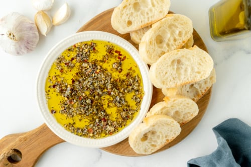overhead shot of olive oil bread dip on board with bread slices