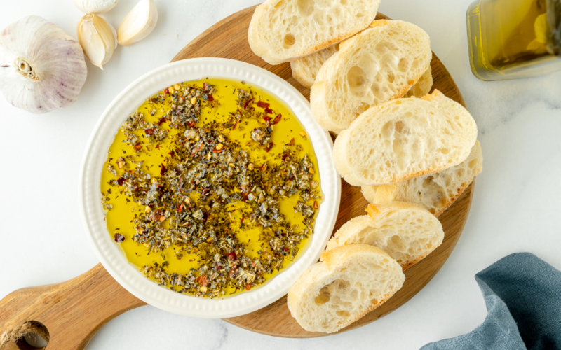 overhead shot of olive oil bread dip on board with bread slices