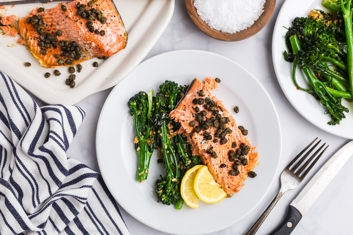 overhead shot of caper salmon on plate with broccolini and lemon