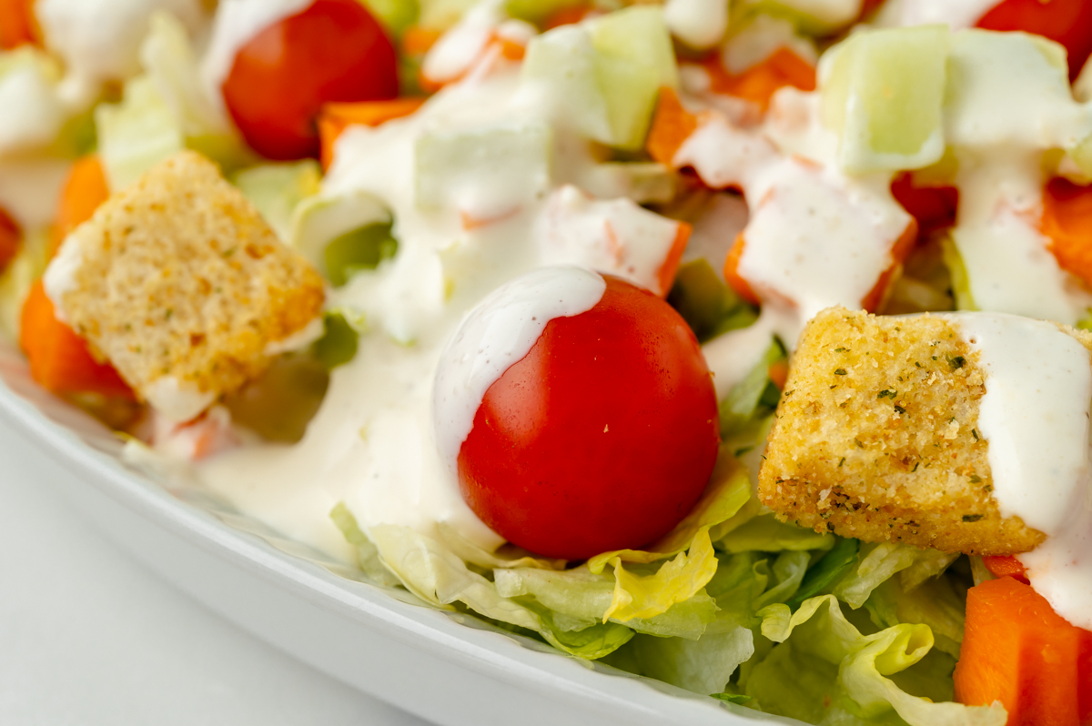 angled shot of salad topped with Parmesan Peppercorn Dressing