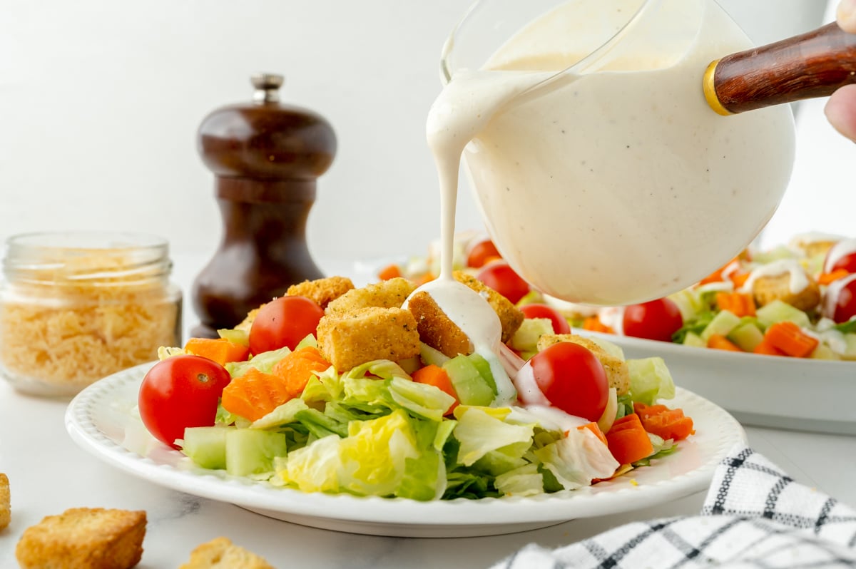 straight on shot of Parmesan Peppercorn Dressing pouring onto salad