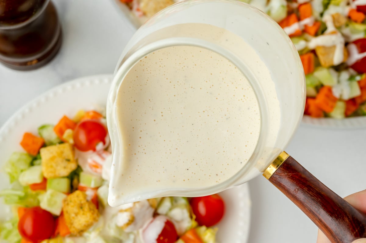 overhead shot of Parmesan Peppercorn Dressing pouring over salad