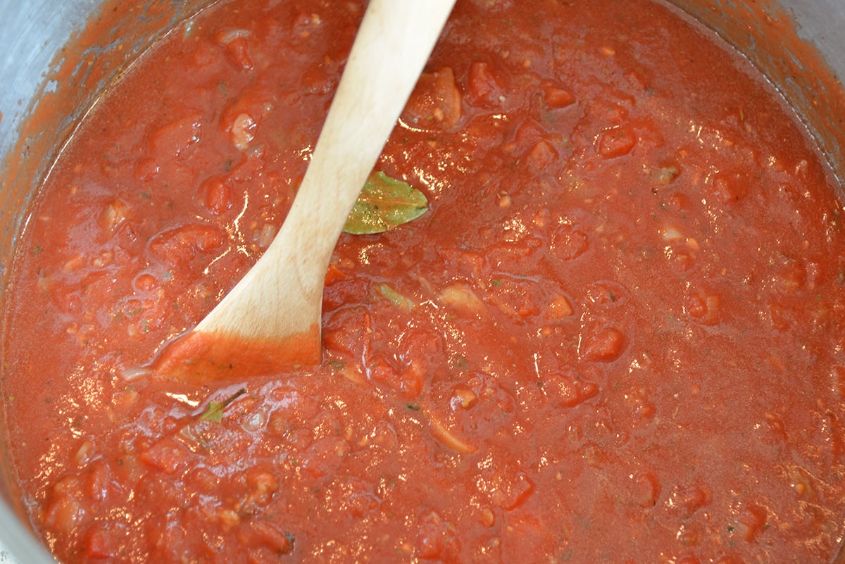 close up overhead shot of wooden spoon in pot of sauce