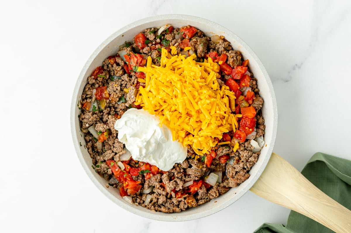 ground beef, tomatoes, sour cream and cheese in a pan