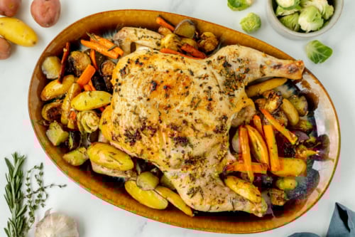 overhead shot of spatchcock chicken in bowl of veggies