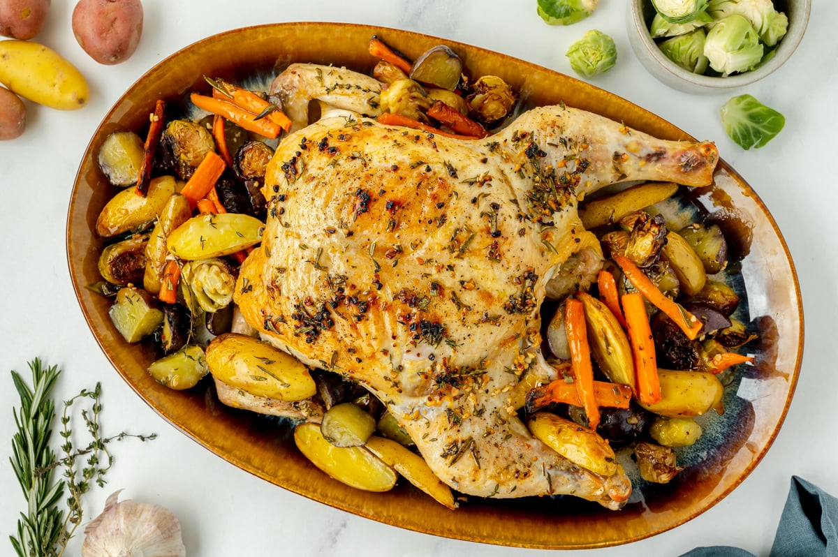 overhead shot of spatchcock chicken in bowl of veggies