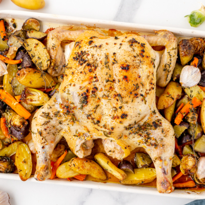 overhead shot of whole chicken on sheet pan with veggies